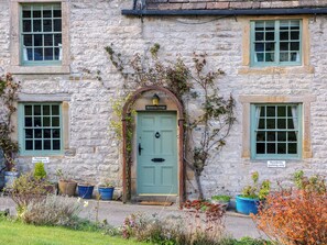Un bâtiment en pierre avec une porte verte, deux fenêtres et un panneau indiquant : « Stationnement réservé aux résidents ».