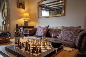 A cozy living room with a chessboard, a bottle of wine, and a lamp. - Buttercup Cottage (Hope Valley)