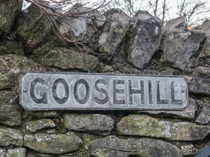 A stone wall with a metal sign that reads "GOOSEHILL". - Buttercup Cottage (Hope Valley)