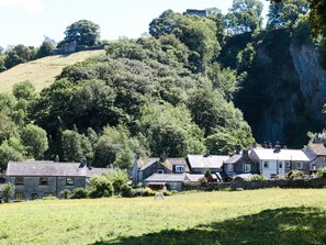A rural setting with stone houses, a field, and a forested hill. - Buttercup Cottage (Hope Valley)