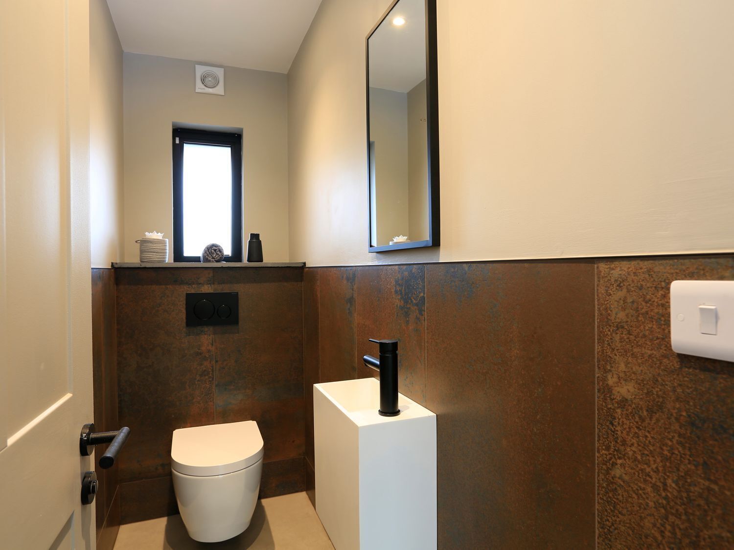 Een kleine badkamer met een toilet, een wastafel en een spiegel.