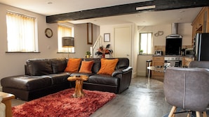 A living room with a black leather sofa, a red shag rug, and a wooden coffee table. - Little Willow (St. Columb Major)