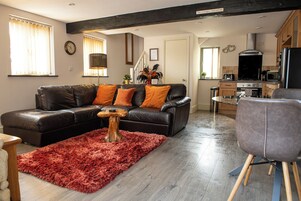 Una sala de estar con un sofá de cuero negro, una alfombra mullida roja y una mesa de centro de madera.