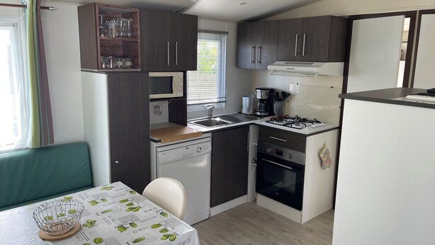 A compact kitchenette with a microwave, stove, and sink. - Welcome to Lily's Mobile Home (Bernières-sur-Mer)