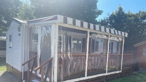 A small, single-story cabin with a wooden deck and a covered porch. - Welcome to Lily's Mobile Home (Bernières-sur-Mer)
