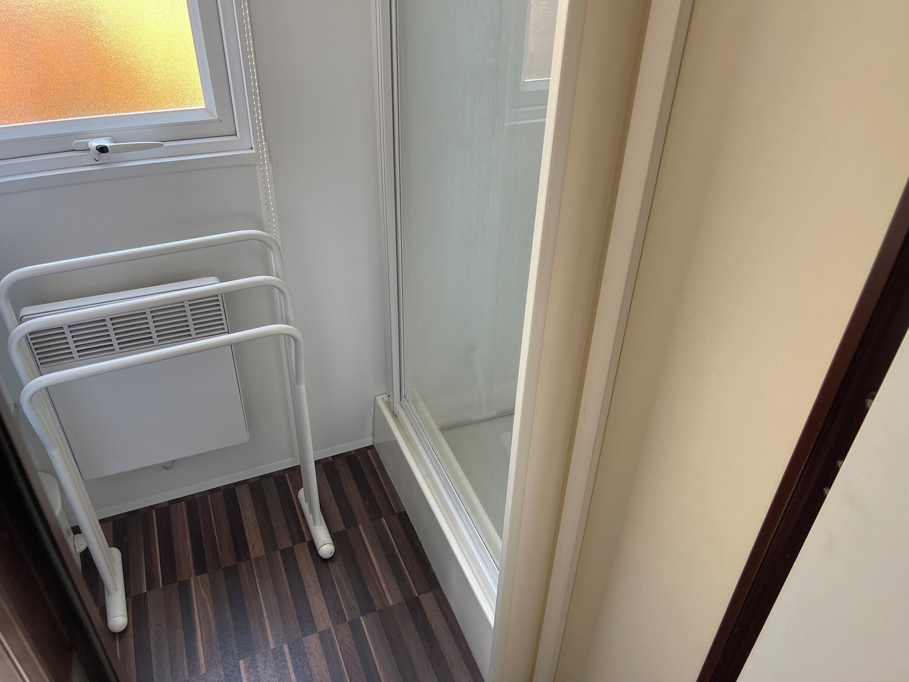 Un coin de pièce avec un radiateur blanc, une fenêtre et une porte.
