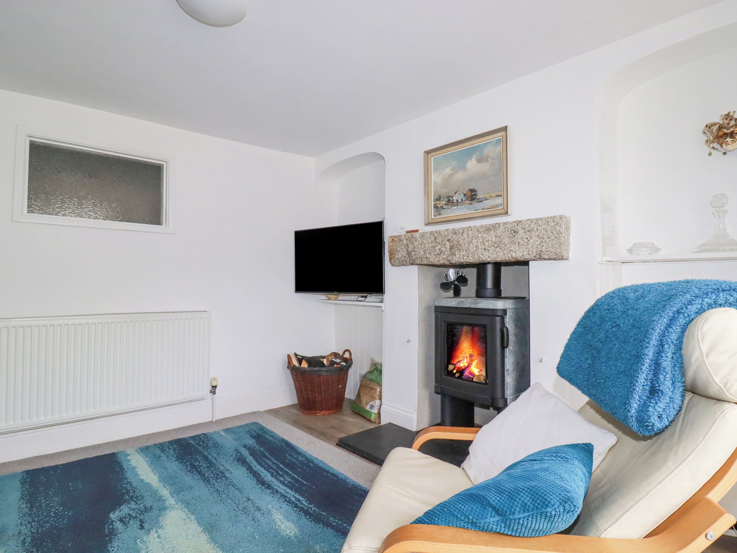 A living room with a fireplace, a television, and a blue rug.