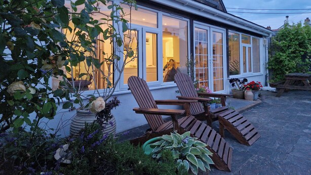 Una casa con un ventanal grande, una terraza de madera y un jardín.