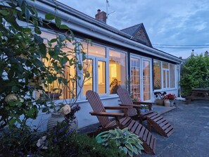 A house with a large window, a wooden deck, and a garden. - Langurra (Newquay)