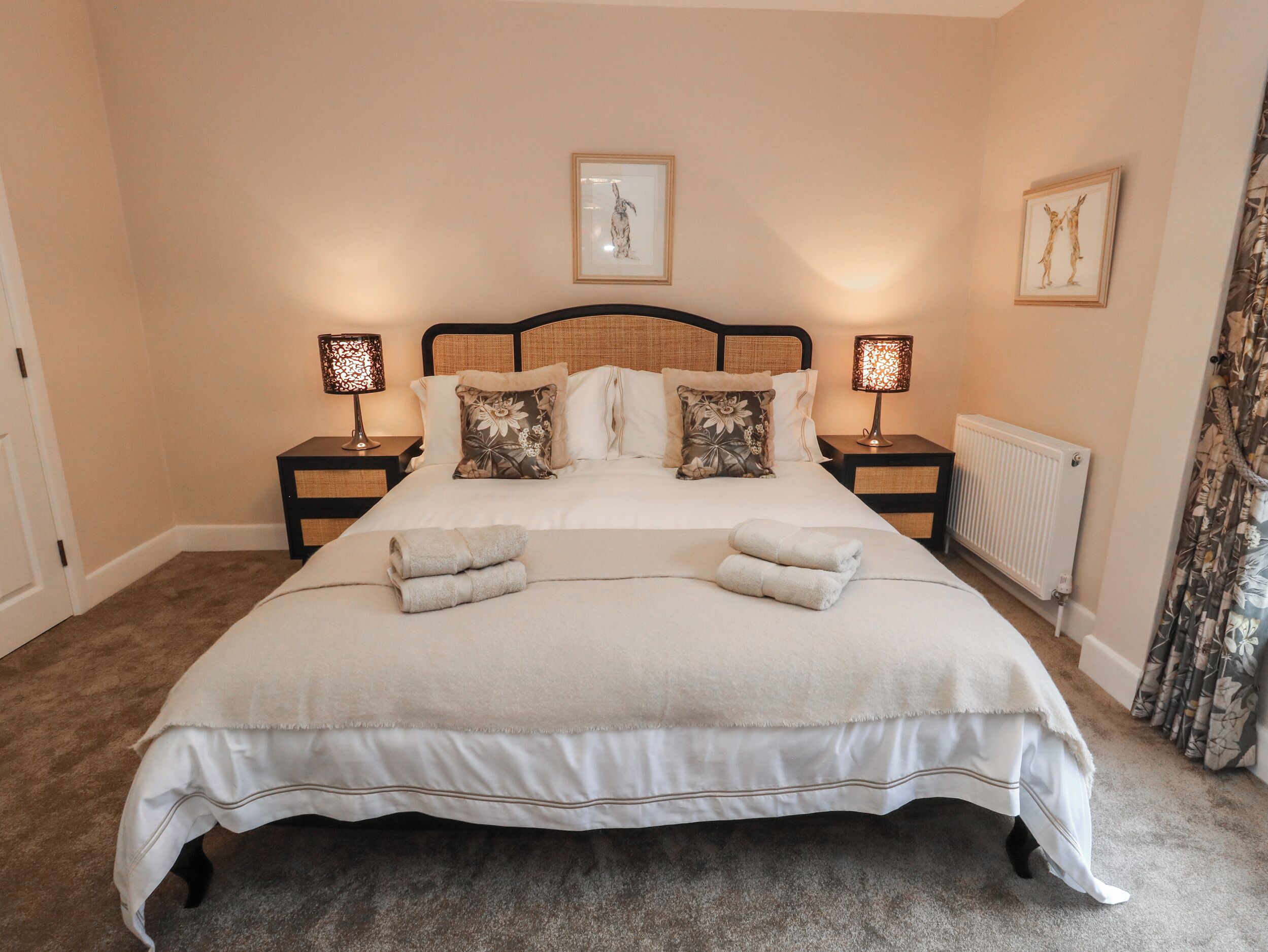 A neatly made bed with two pillows, two bedside tables with lamps, and a framed picture on the wall.