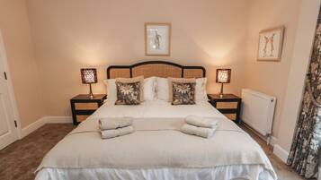 A neatly made bed with two pillows, two bedside tables with lamps, and a framed picture on the wall.