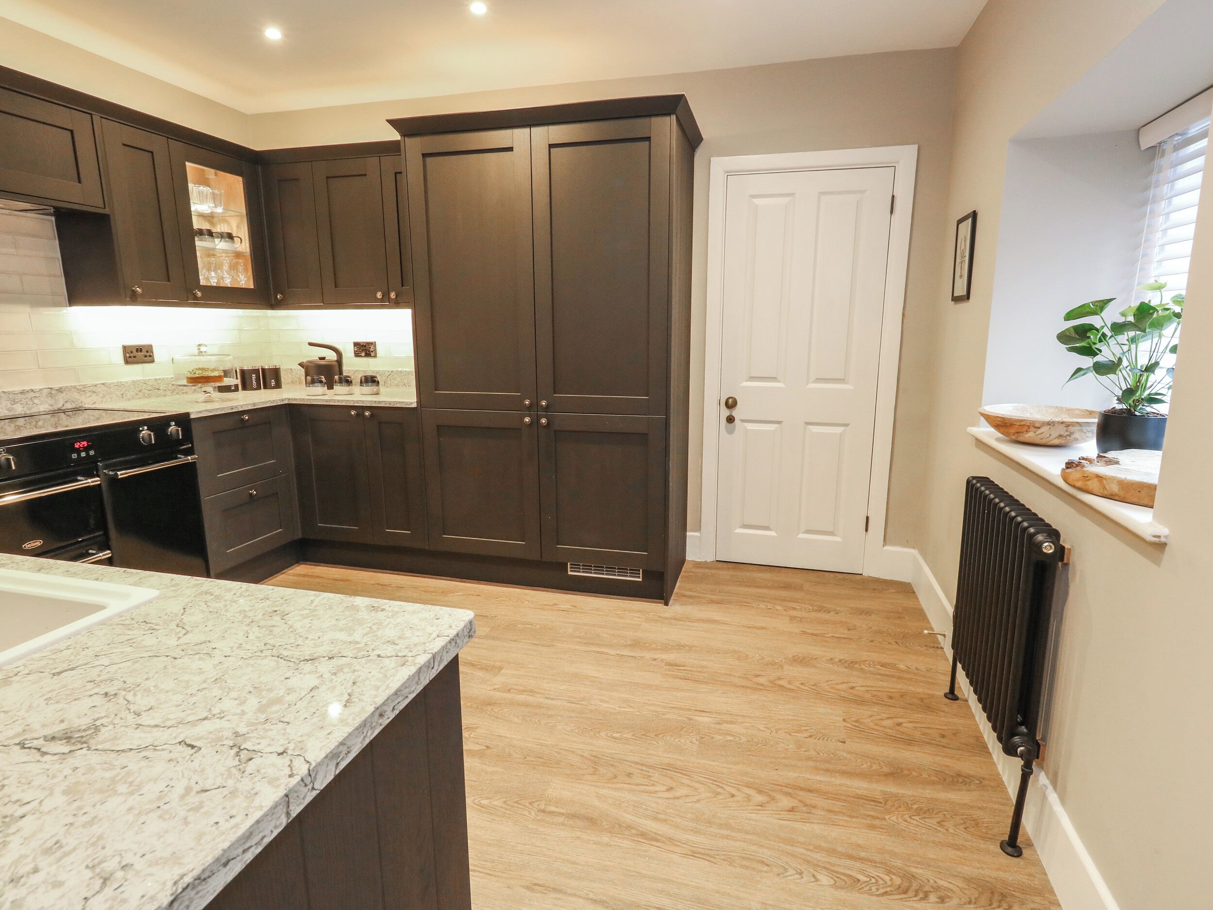 Una cocina con armarios de madera oscura, encimera de mármol y una puerta blanca.