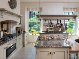 A kitchen with a central island, white cabinetry, and a window with a view of greenery.
