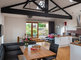 A modern kitchen with a dining area, large windows, and a view of the garden.