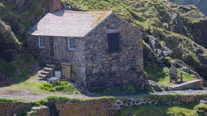 Une petite maison en pierre avec un toit en pente, une petite fenêtre et une porte.