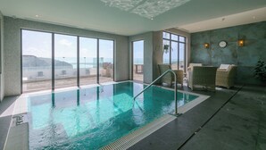 Une piscine intérieure offrant une vue dégagée sur l’océan, de grandes fenêtres et un plafond doté d’un système d’éclairage original.