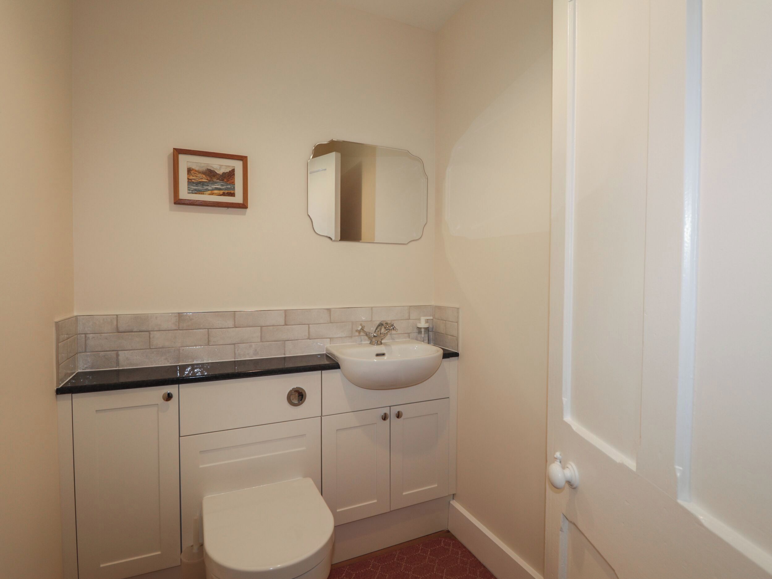 Ein kleines Badezimmer mit Toilette, Waschbecken und Spiegel.