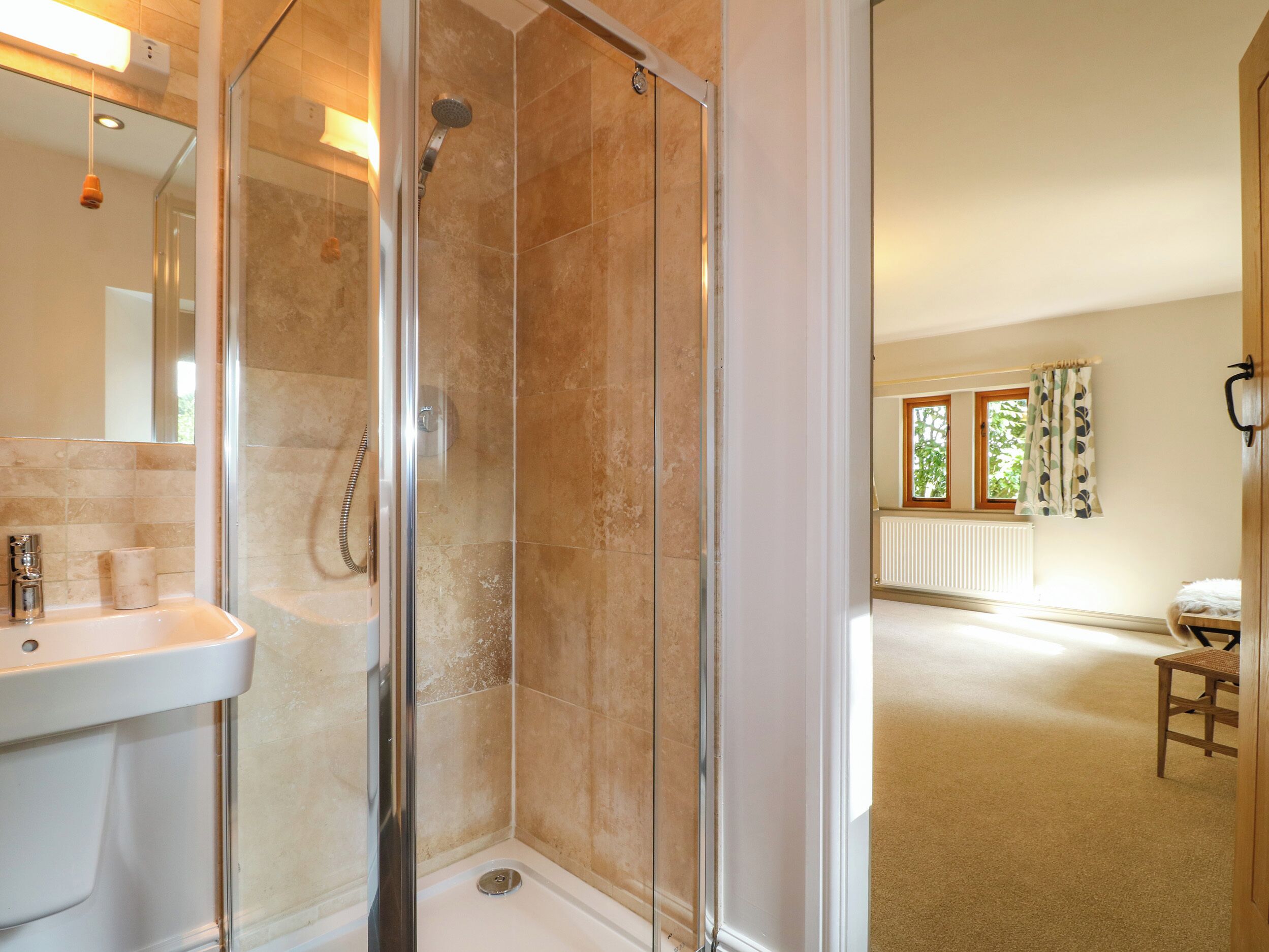 A bathroom with a glass-enclosed shower, a sink, and a mirror.