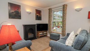 A living room with a fireplace, two sofas, a TV, and a window with curtains. - New Tower House- 10 Pear Tree Court (York)