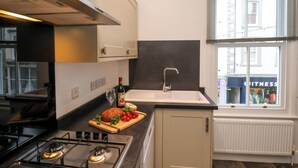 Una cocina moderna con estufa a gas, un lavaplatos y un ventanal con vista a un edificio.