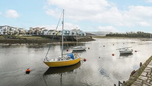 Une rivière paisible où sont amarrés plusieurs bateaux, entourée de bâtiments modernes dotés de balcons.
