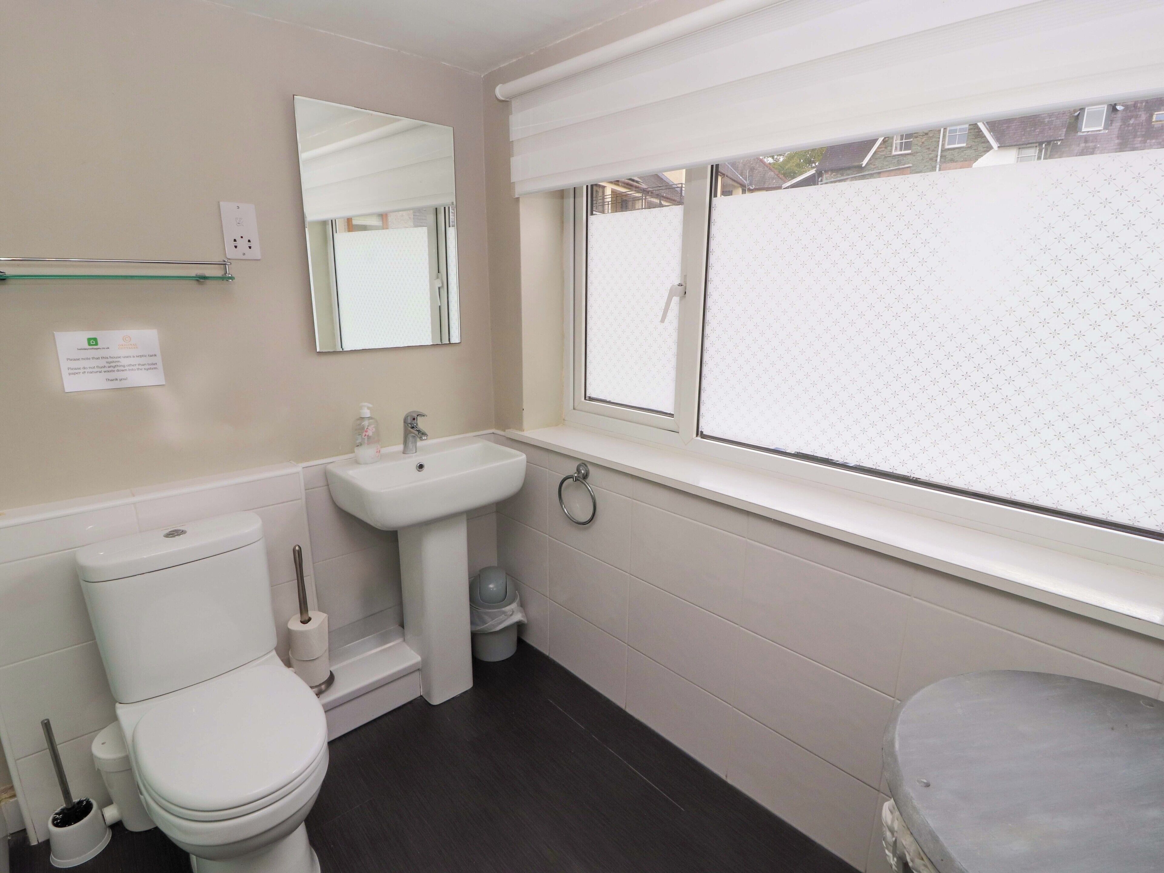 A bathroom with a toilet, sink, and window.