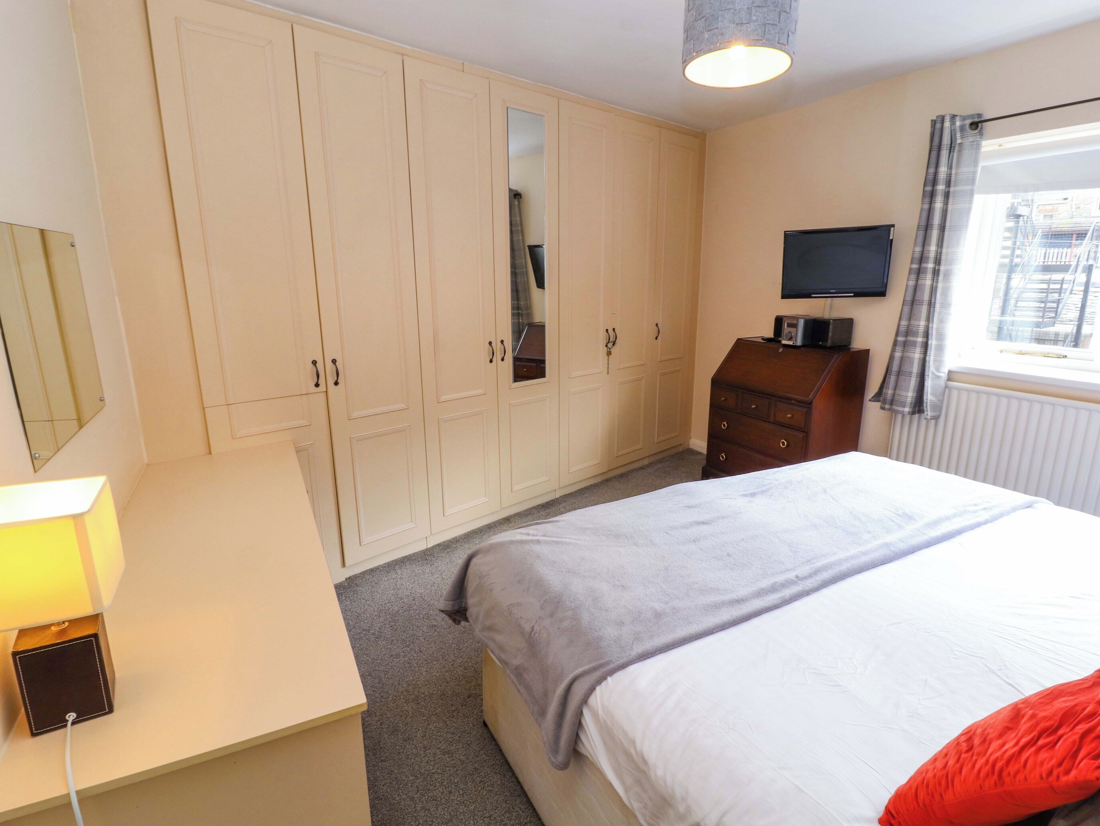 A bedroom with a bed, a dresser, a TV, and a wardrobe.