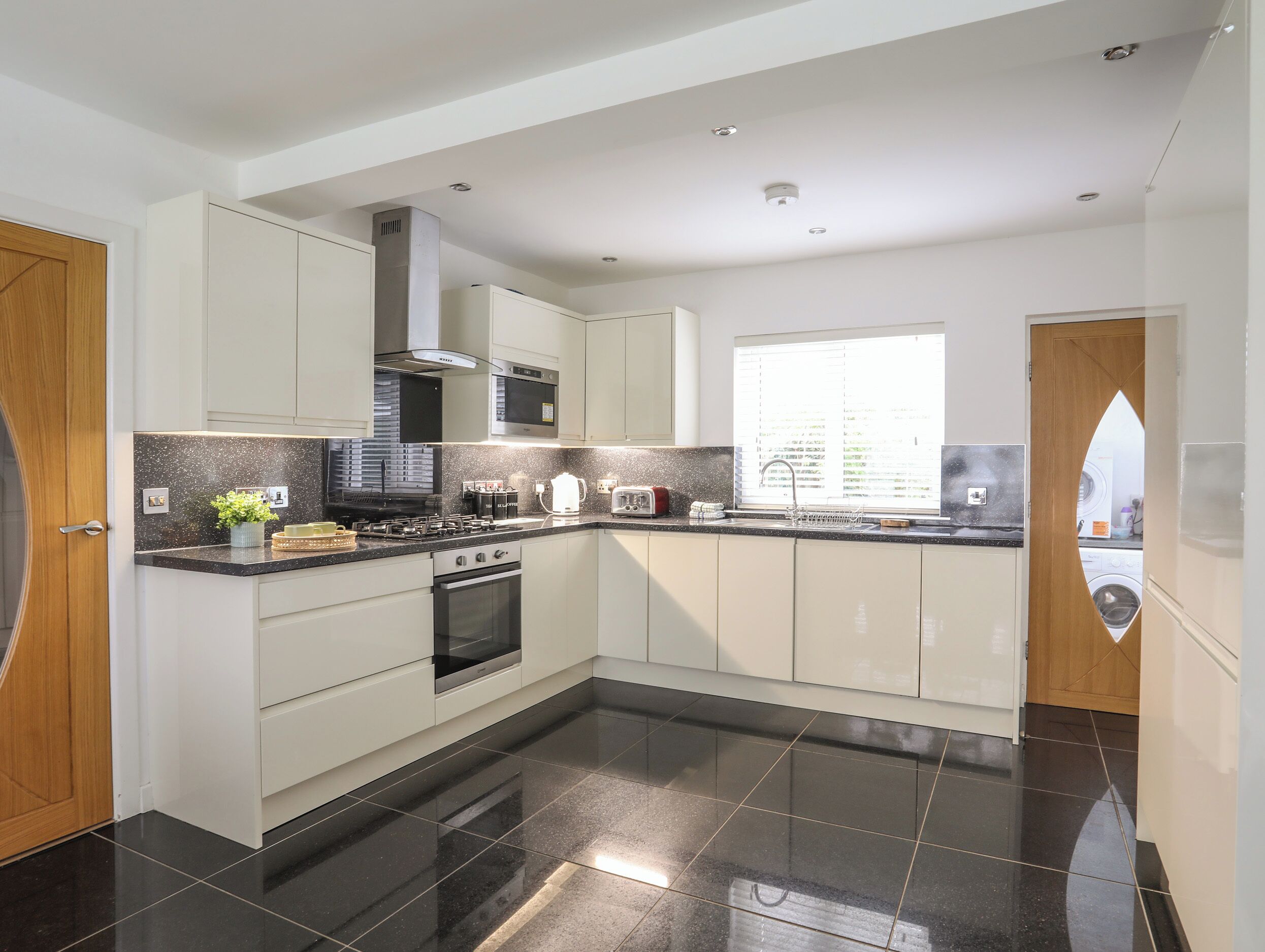 A modern kitchen with white cabinets, a black countertop, and a stainless steel range hood.
