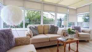 A spacious room with a large window, a wicker sofa, a wooden coffee table, and a fluffy white decoration. - Monarfon (Criccieth)