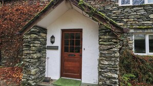 A stone house with a wooden door, a small porch, and a sign that reads "Riverside".