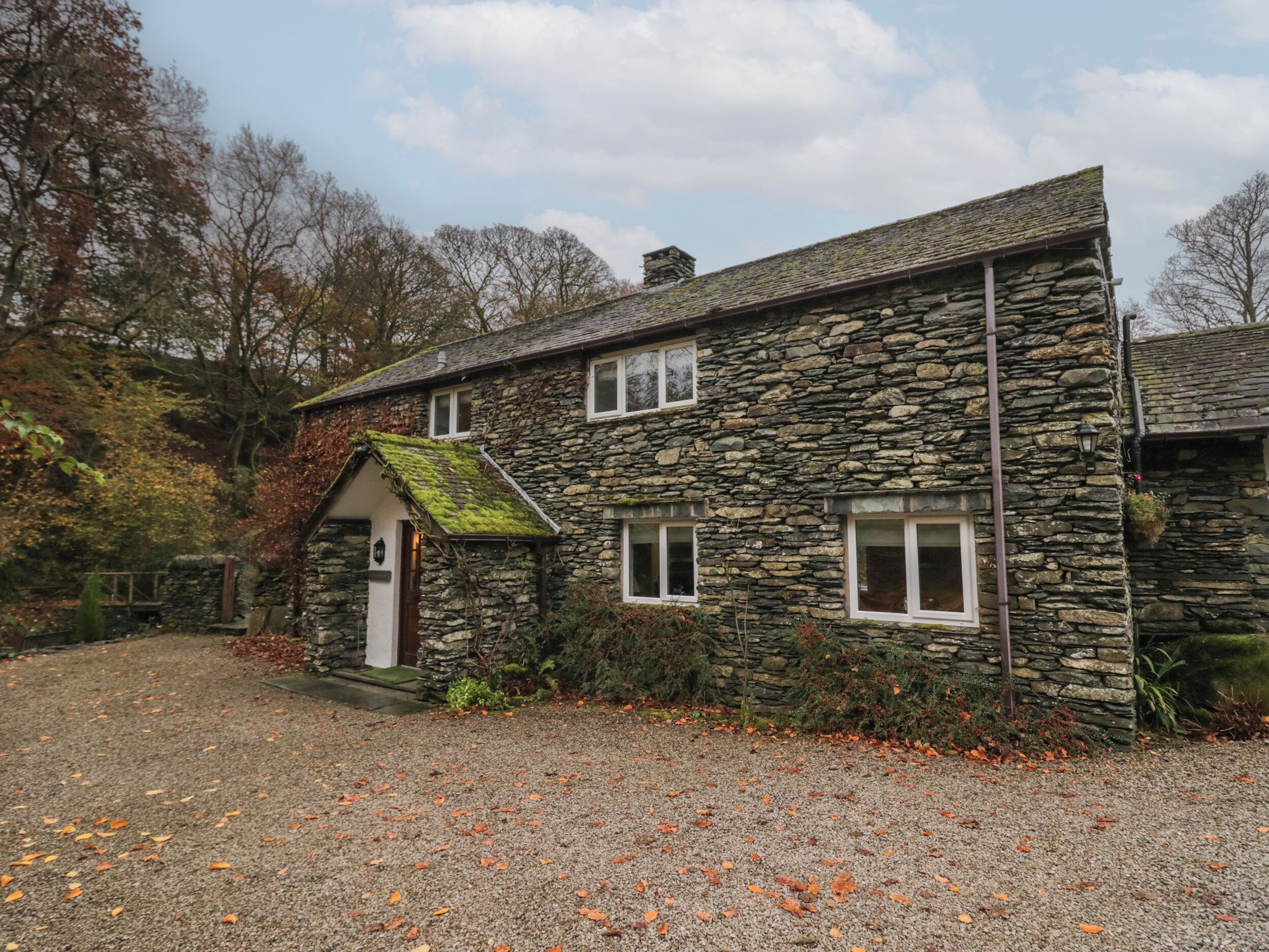 A stone house with a gravel driveway and a small porch.