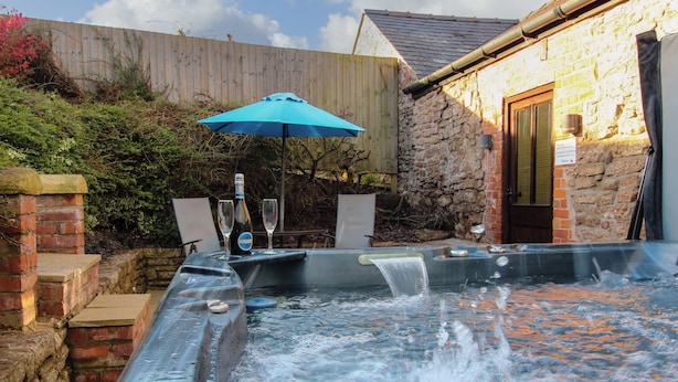Un bain à remous avec un parasol bleu, une bouteille et deux verres.