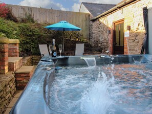 A hot tub with a blue umbrella, a bottle, and two glasses. - The Cart House (Shrewsbury)