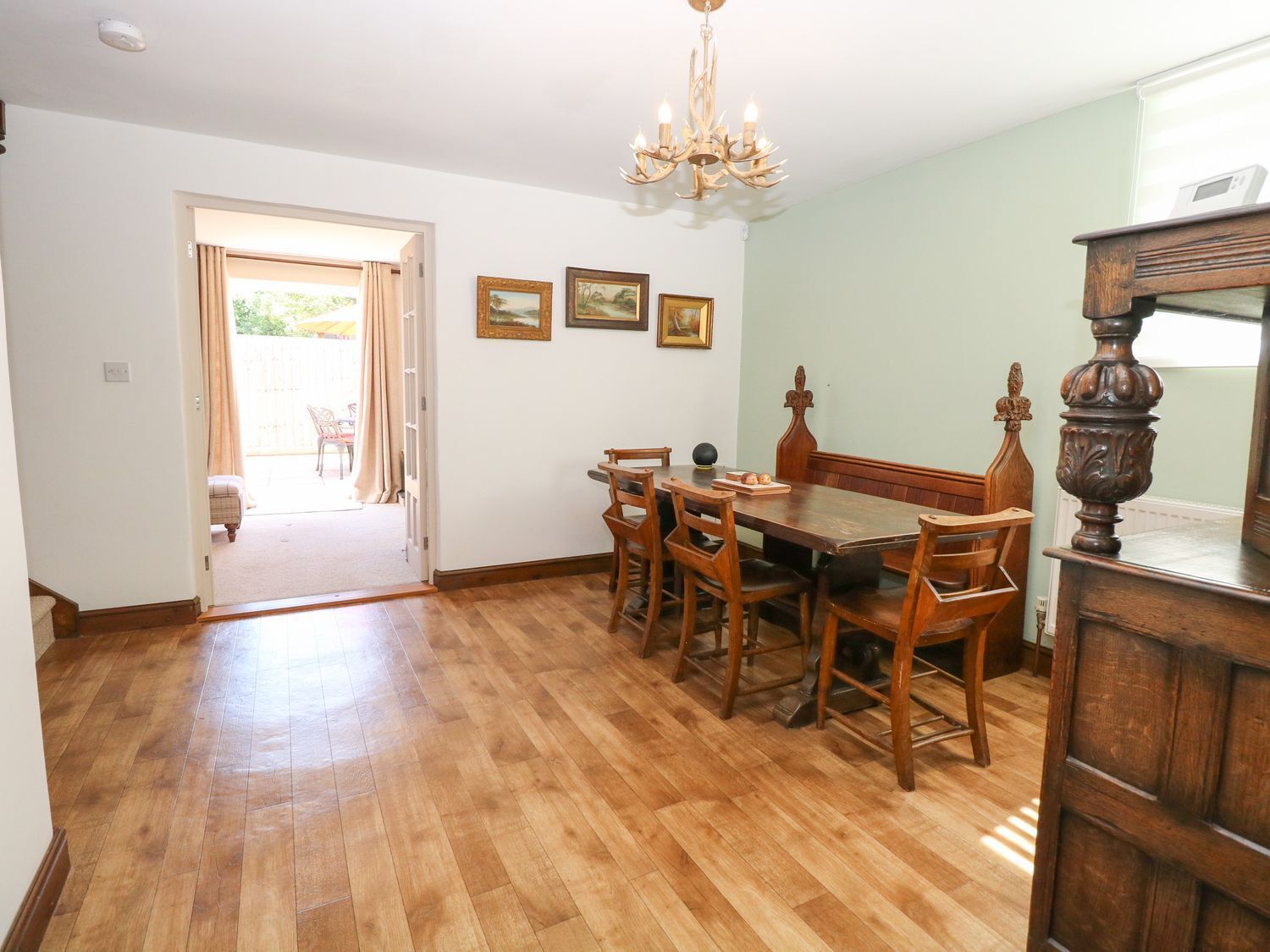Ein Essbereich mit Holztisch und Stühlen, einer Kristallleuchtre und gerahmten Kunstwerken an der Wand.