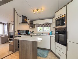 Una cocina moderna con una isla central, electrodomésticos integrados y una zona de comedor con sofá.