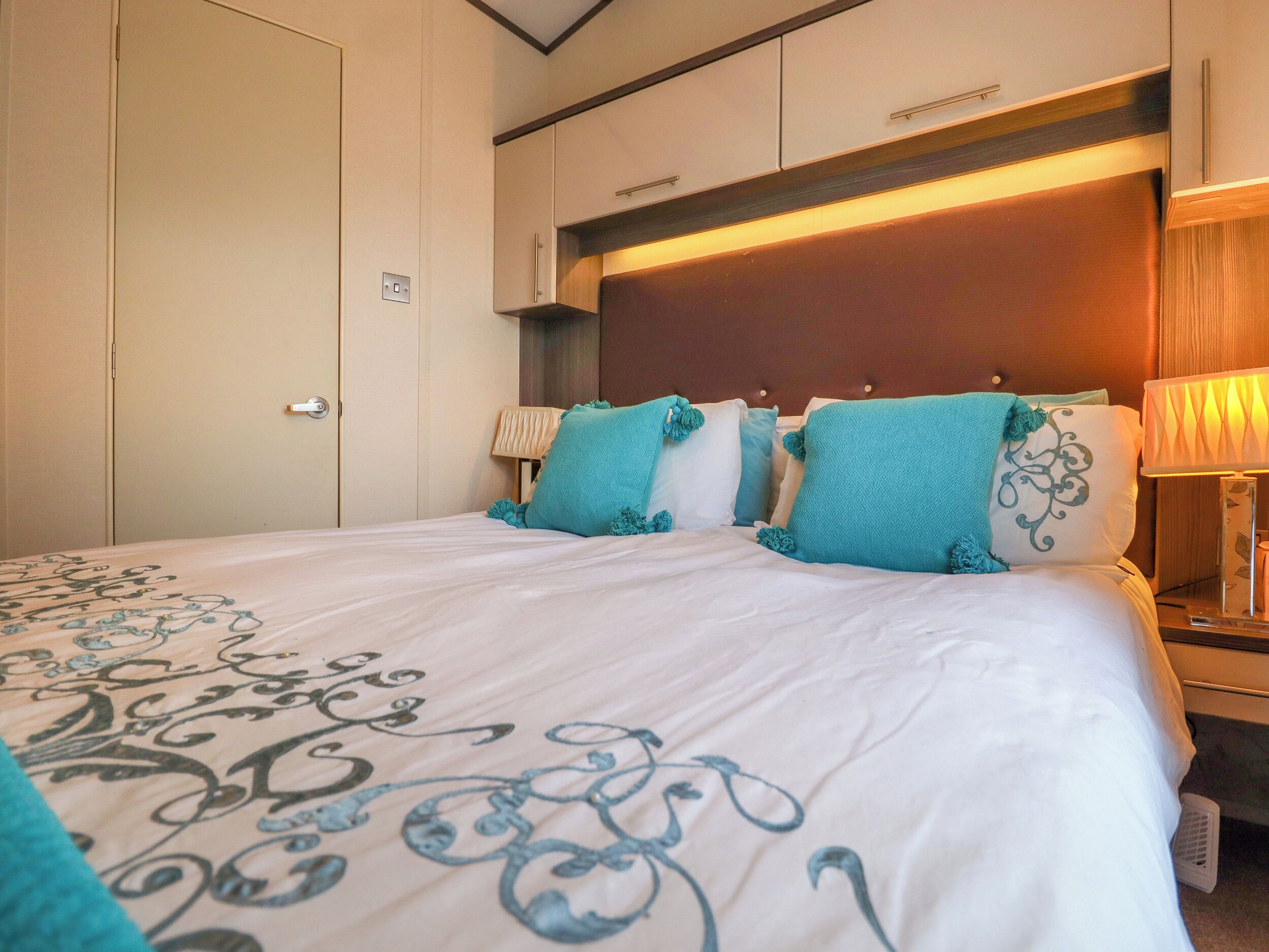 Une chambre d’hôtel avec un grand lit, une tête de lit en bois et une table de chevet avec une lampe.