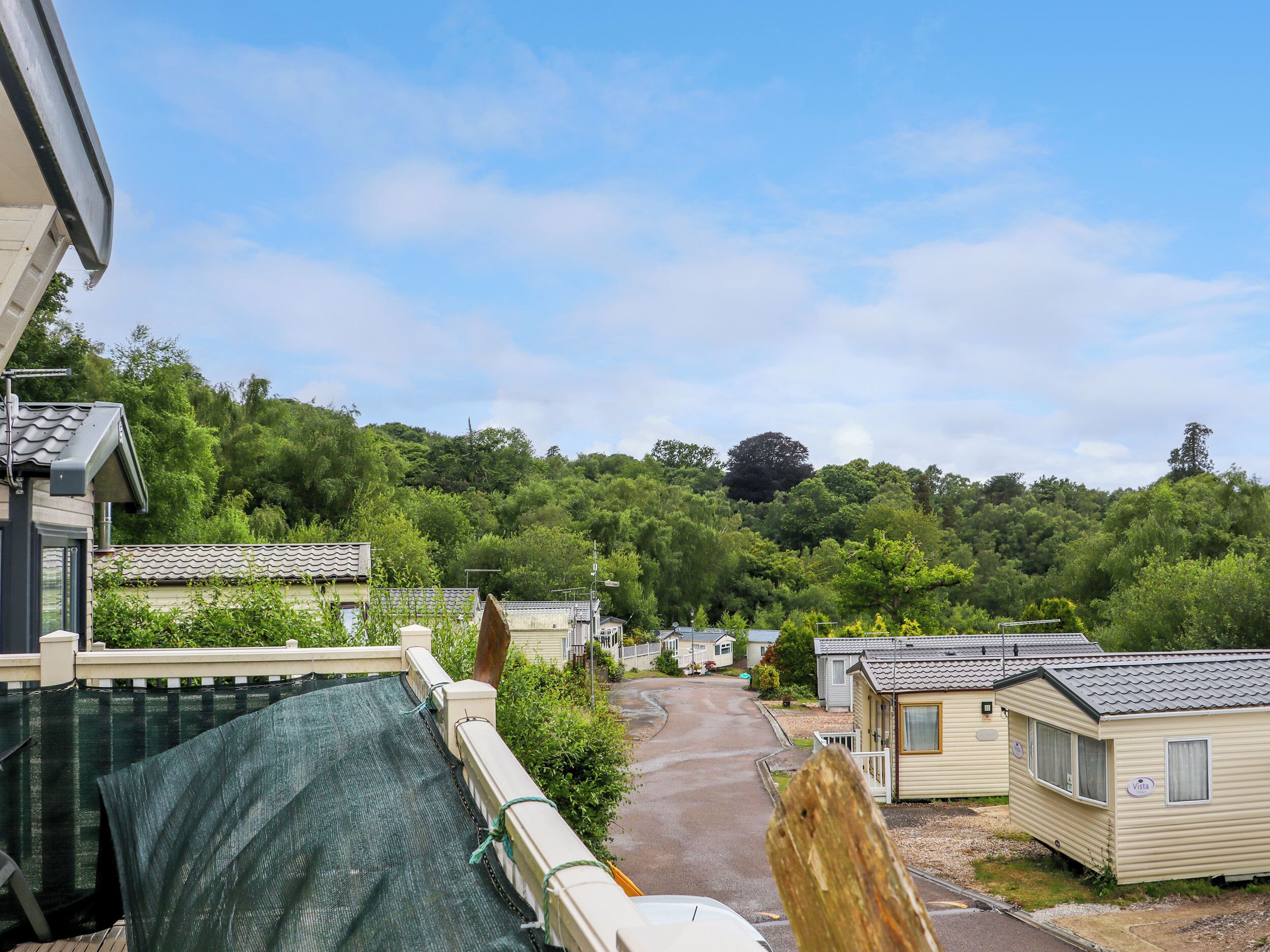 A row of mobile homes with a paved driveway leading to a hill.