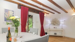 Un coin repas avec une table blanche, des rideaux rouges et un plafond en bois.