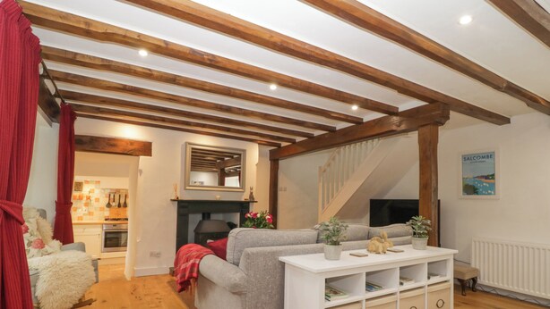 Un salon chaleureux avec une cheminée, un canapé, une console blanche et un escalier menant à un autre niveau.