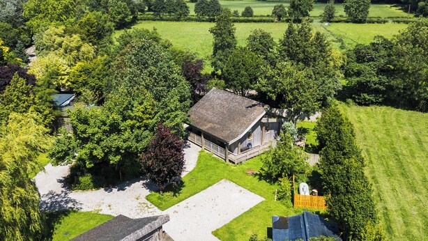 Een landelijke woning met een groot huis, omringd door weelderige begroeiing en velden.