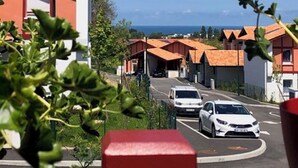 Ein Parkplatz mit mehreren Autos, ein Gebäude mit orangenen Dächern und einem strahlend blauen Himmel.