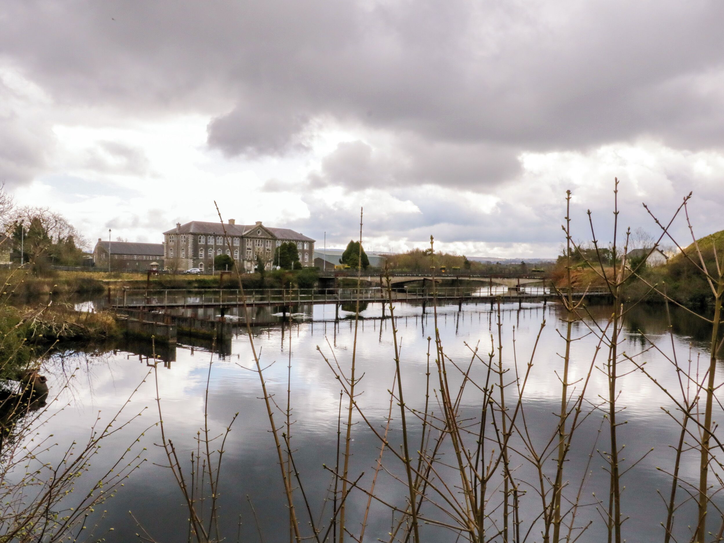 A calm river with a bridge and a large building in the background.