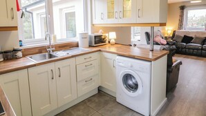 A compact kitchen with a washing machine, a microwave, and a sink. - 4 Carlton Cottages (Enniskillen)