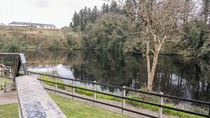 A riverside walkway with a concrete bench, metal railing, and a tree. - 4 Carlton Cottages (Enniskillen)