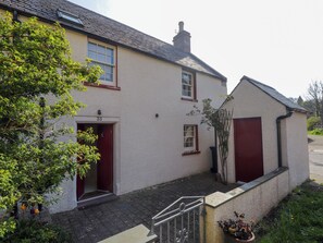 A two-story house with a red door and windows, number 35, with a small garden and a metal gate.