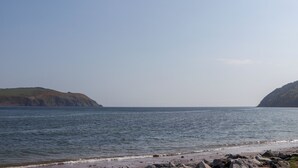 A coastal landscape with a rocky beach and calm sea. - Seashell Cottage (Cromarty)