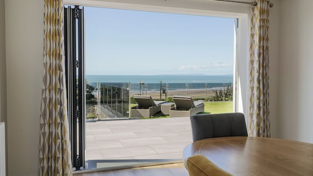 A room with a large sliding glass door leading to a balcony with a view of the beach and ocean. - Melin Y Plas (Barmouth)
