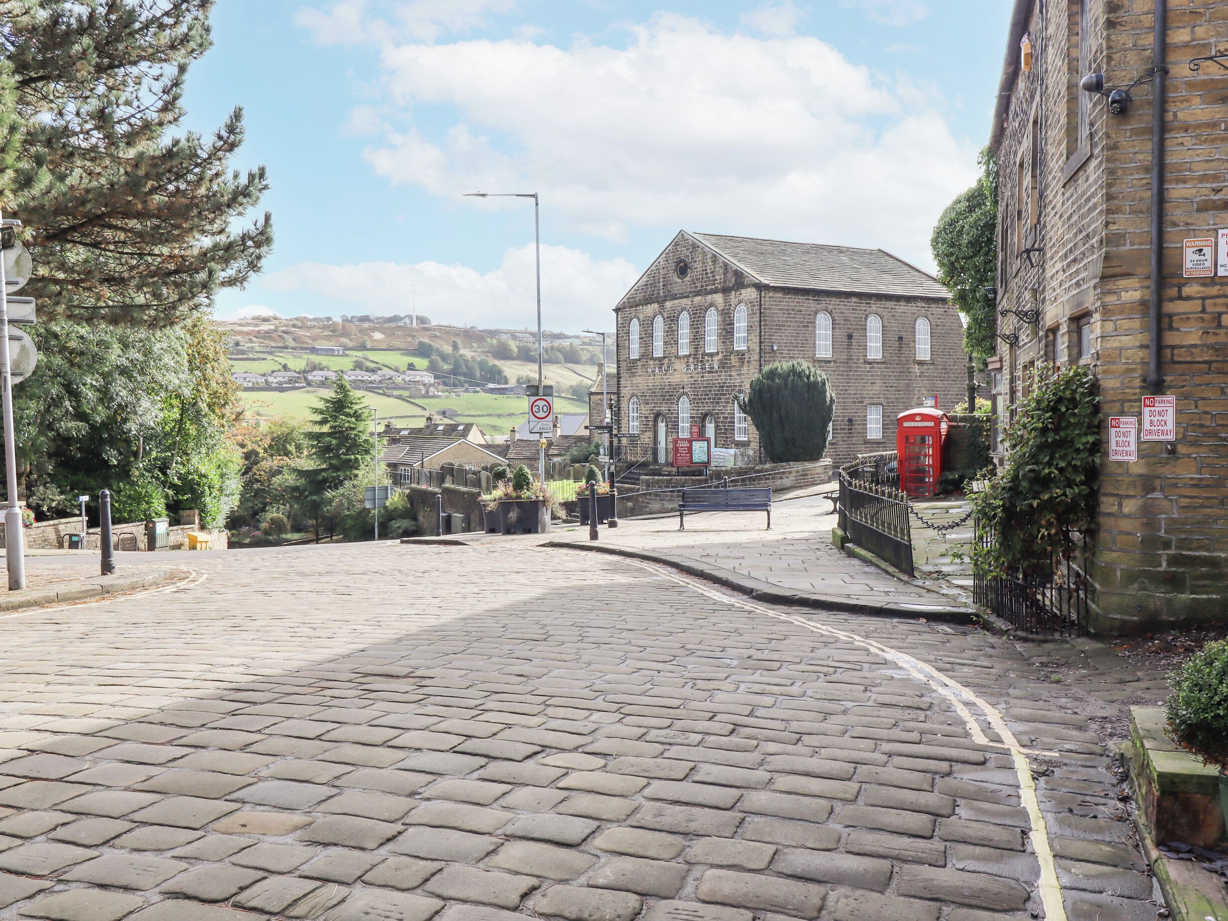 A cobblestone street leading to a historic building with a traditional brick facade and arched windows.