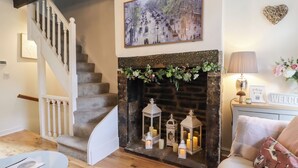 A cozy living room with a fireplace, a staircase, and a painting on the wall. - The Snug on the Cobbles (Keighley)