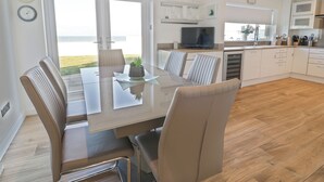 Ett modernt kök med matplats, stora fönster och utsikt över havet.